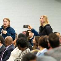 three people standing in line to ask question at microphone